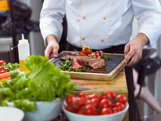 Wall Mural - closeup of Chef hands serving beef steak