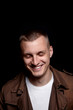 © vania_zhukevych - Close-up portrait of young handsome man.Three days unshaved.Laughing hansdome man. on dark background .Modern and dramatic photo.In brown coat and white t-shirt.Emotion. Blue eyes