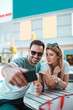 © Nebojsa - Happy young couple having ice-cream and taking selfie enjoying sunny day outside.