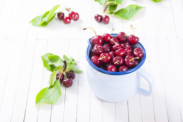 Sticker - Cherry in old enamel mug, white wood table background