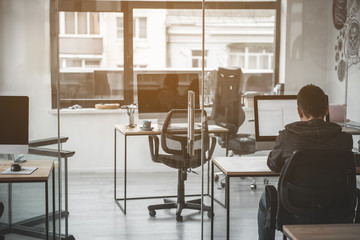 Poster - Man typing in digital device while turning back to camera. He sitting at table in office. Employer at job concept