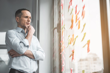 Poster - Portrait of pensive businessman touching chin by hand while looking at sticky notes on window. Creativity concept