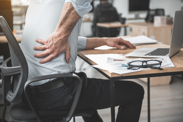 Poster - Employer having pain in back. He holding it by hand while sitting at table during job. Worker with bad state of health concept