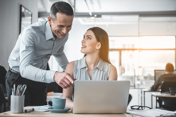 Poster - Outgoing female partner looking at glad man while typing in gadget. They talking during job. Friendly professional communication concept