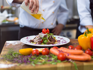 Chef finishing steak meat plate