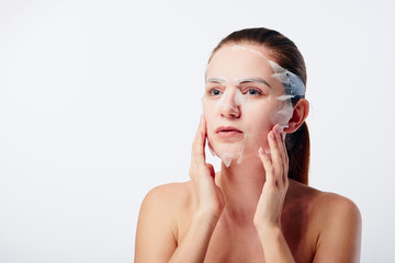 Young woman with sheet mask on her face