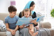 Muslim woman reading book to her children at home