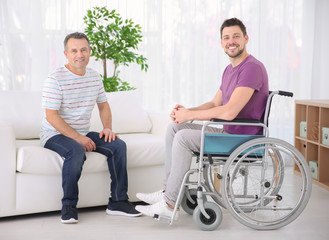 Wall Mural - Mature man and his son in wheelchair indoors