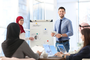 Canvas Print - Muslim businesswoman and her coworker showing presentation on meeting