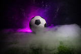 Fototapeta Sport - Traditional soccer ball on soccer field. Close up view of soccer ball (football) on green grass with dark toned foggy background.