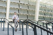 © LIGHTFIELD STUDIOS - handsome young man walking down stairs in front of stadium with book and coffee to go