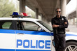 © LIGHTFIELD STUDIOS - handsome african american police officer with crossed arms leaning back on car and looking at camera