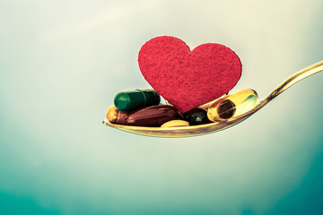 Wall Mural - the colorful medical supplement and drug pills with red heart in spoon , pharmaceutical cardiology drugs for heart health care disease concept