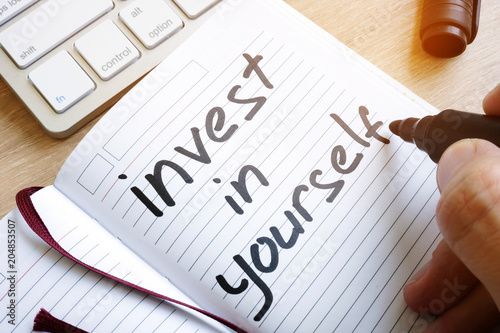 Fotografía Man is writing invest in yourself in a note.