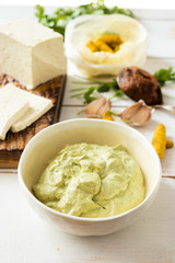 Asian tofu cheese dip sauce with parsley, turmeric, celery, garlic, miso paste in white bowl. Raw, vegan, vegetarian healthy food concept.