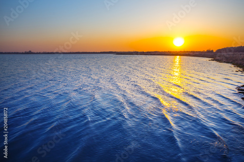 Plakat cichy zachód słońca nad małym niebieskim jeziorem