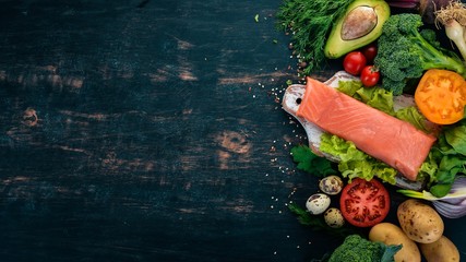 Salmon fillet and fresh vegetables. Healthy food. On a black wooden background. Healthy food. Top view. Copy space.