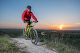 Fototapeta Lawenda - A cyclist in a red jacket rides a bike along the mountain path. The concept of extreme sports. Mountain bike.