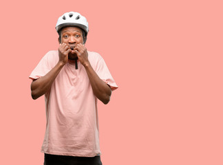 Wall Mural - Black man wearing bike helmet terrified and nervous expressing anxiety and panic gesture, overwhelmed