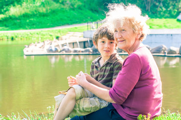 Wall Mural - Happy grandmother with her grandson rest on the lake together