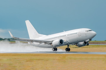 An airplane lit by the sun takes off in a wet runway during the rain at the airport.