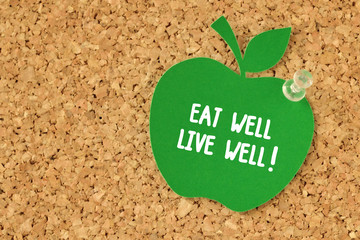 eat well, live well! written on apple shaped paper note on pinboard