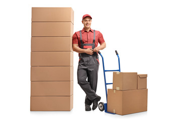 Wall Mural - Mover with a hand truck leaning on a stack of boxes and smiling