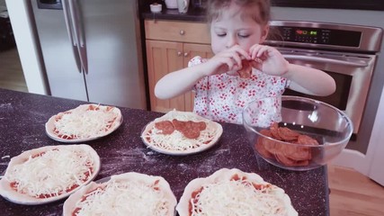 Canvas Print - Little girl making home made small pepperoni pizzas