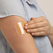 YOUNG WOMAN APPLYING TRANSPARENT NICOTINE PATCH TO ARM