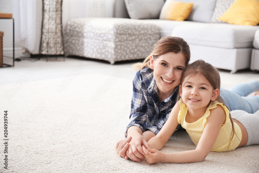 Cute little girl and her mother lying on cozy carpet at home Stock ...