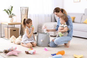 Poster - Housewife and children picking up toys after playing at home