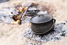 Cast Iron Pot Being Used To Cook A Camping Meal With Coals And A Wood Burning Camp Fire