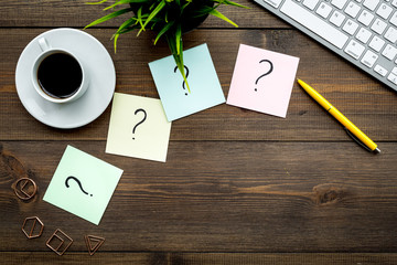 Poster - Question mark on sticky notes on office desk on dark wooden background top view copy space. FAQ concept. Working with clients. Troubles in work.