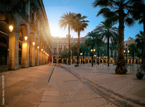 Plakat Słońce wznosi się nad oświetlonym Plaza Real w gotyckiej dzielnicy Barcelony w Hiszpanii