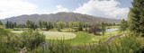 Fototapeta Do pokoju - Panoramic of mountains with golf course green, pond and cart path on a summer day
