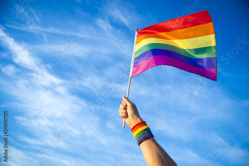 Fotomural Colorful backlit rainbow gay pride flag being waved in the breeze against a sunset sky