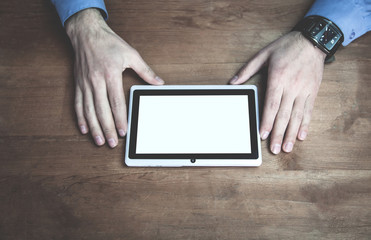 Hands using tablet white screen display on wooden desk.