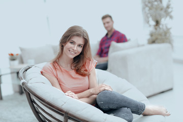 Wall Mural - smiling young woman sitting in a large comfortable chair