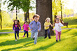 many young children smiling running along the grass in the park. Childhood, Children's Day, vacation, vacation, adventure, friendship.
