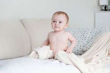 Wall Mural - Cute baby boy sitting on big bed at bedroom