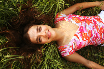 young beautiful girl lays on a grass 