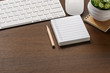 Mockup of white keyboard, mouse, to do list note, pencil and houseplant on wooden table