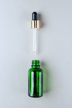 Minimalist Photo Of Skin Care, Packaging For Cosmetics. Green Glass Bottle With A Pipette In Pastel Colors. Flat Lay.