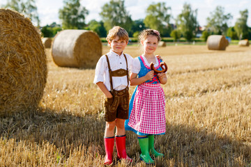 Wall Mural - Two kids, boy and girl in traditional Bavarian costumes in wheat field