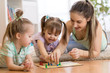 © Oksana Kuzmina - Mother and kids daughters sitting in a playroom, playing a ludo game and enjoying their time together