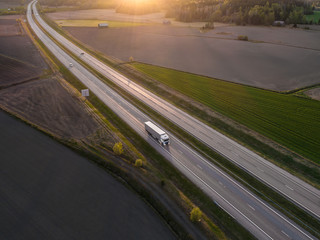 Aerial view of highway with cargo truck driving by at spring sunset