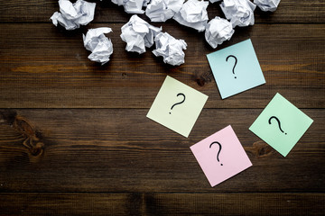 Poster - FAQ concept. Question mark on sticky notes near crumpled paper on dark wooden background top view copy space