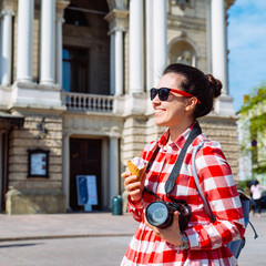 Wall Mural - tourist woman with photo camera and ice cream in the middle of european city