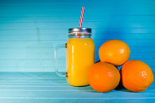 Freshly Squeezed Orange Juice In A Jar With A Handle On A Turquoise Background, Copy Space