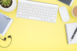 workspace with tablet, keyboard, coffee cup and eyeglasses copy space on yelow background. Top view.